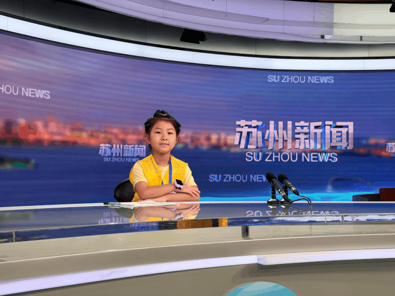 青少年体验新闻主播台进行现场播报